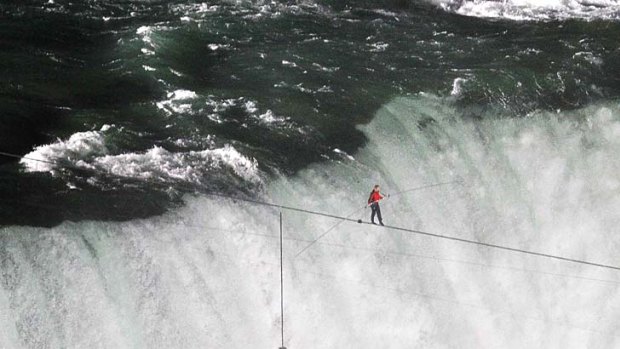 Tightrope walker Nik Wallenda avoids the dangerous plunge below and safely crosses Niagra Falls.