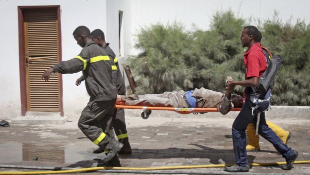 Somali rescuers carry away a severely injured civilian from the scene of a twin bombing attack on Central Hotel in Mogadishu, Somalia.