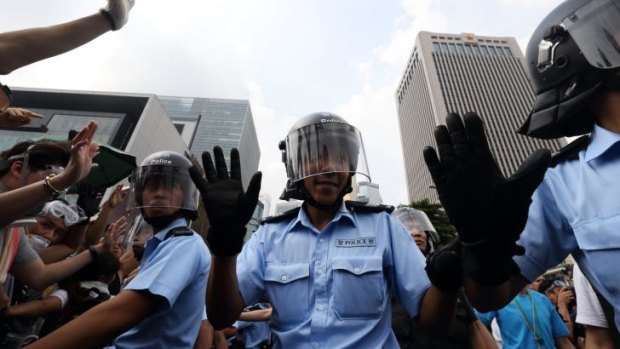 Police officers gesture as demonstrators gather outside the Central Government Offices.