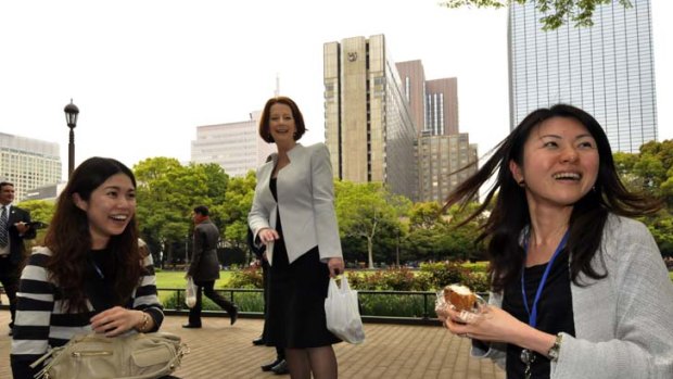 Julia Gillard meets young Japanese women having lunch in a Tokyo park yesterday and enjoys a delicacy herself.