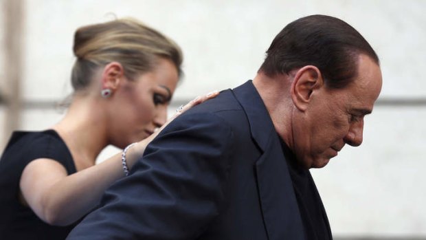 Former Italian Prime Minister Silvio Berlusconi leaves the stage flanked by his girlfriend Francesca Pascale at the end of a rally to protest his tax fraud conviction, outside his palace in central Rome on August 4.