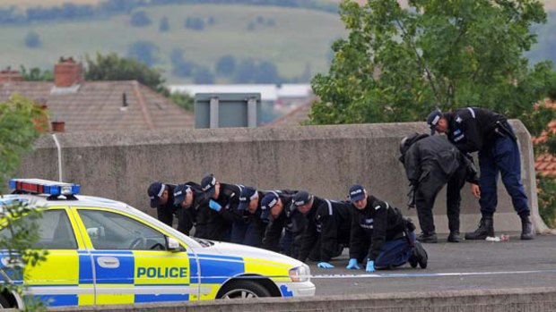 Police officers conduct a fingertip search on the road in Newcastle northern England where a police officer was shot earlier in the day.