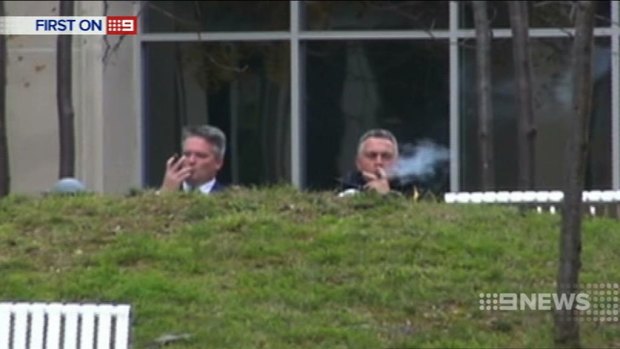 Finance Minister Mathias Cormann and Treasurer Joe Hockey enjoy cigars outside Parliament House in Canberra.