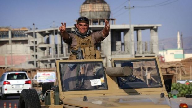 Iraqi Kurdish fighters show their confidence as they drive through Erbil on their way to the Syrian front on Tuesday.