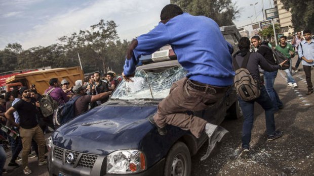 An Egyptian student at Cairo's University smashes a police vehicle during a demonstration.