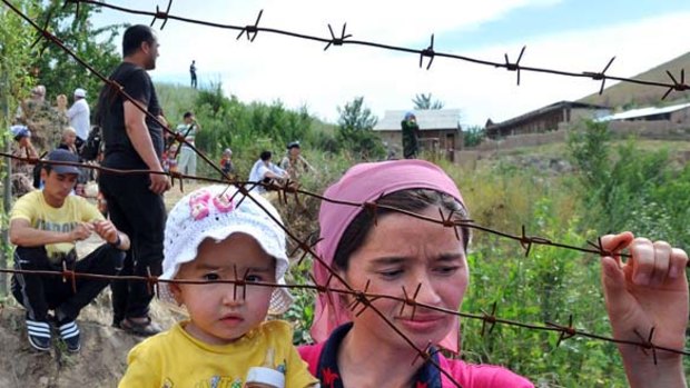 An ethnic Uzbek mother holds her daughter as they wait at the Kyrgyz-Uzbek border.