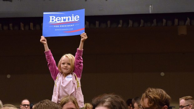 A five-year-old holds up a "Bernie Sanders for President" sign while sitting on her father's shoulders at the Juneau Democratic Caucus in Alaska on Saturday.