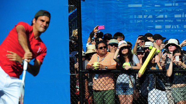 Roger Federer attracts a large gathering for a practice session on the outside courts.