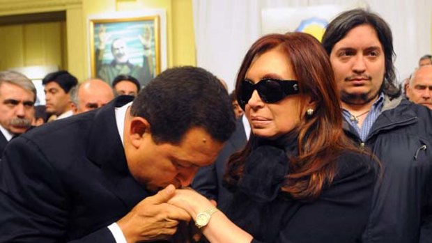 The Venezuelan President, Hugo Chavez, kisses Cristina Kirchner's hand at the wake for her husband as the Kirchners' son Maximo stands by.