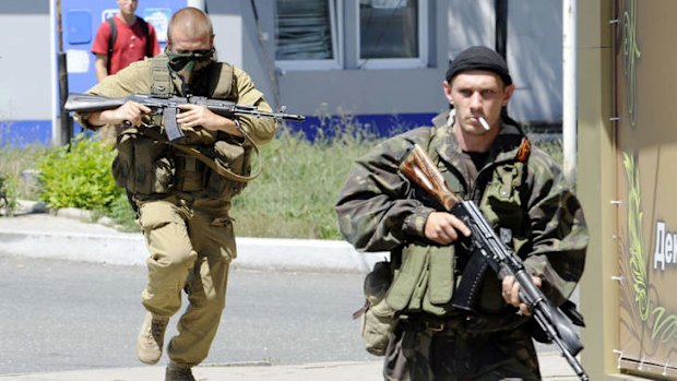 Fighting continues: Armed pro-Russian separatists on the move during clashes that left at least  three people dead in Donetsk.