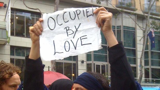 An Occupier holds up a sign. Protesters have called for people to join them at 9am.