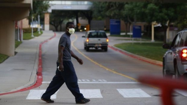 Precautions: A pedestrian wears a surgical mask as he crosses the street in front of Texas Health Presbyterian Hospital, where Thomas Eric Duncan is being treated.  