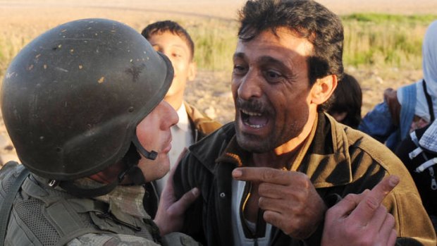 A Syrian man argues with a Turkish soldier while trying to cross the border during a bombardment that killed 18 people.