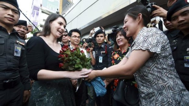 Flower power: A pro-military protester hands an Australian embassy official a bouquet of roses outside the embassy in Bangkok.