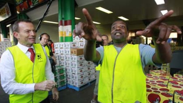 Opposition Leader Tony Abbott is greeted by worker Darius Kabengere during a visit to the Brisbane Produce Markets in Brisbane.