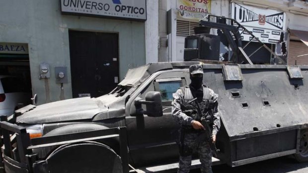 Armoured behemoth ... a policeman in Guadalajara guards a gang vehicle.