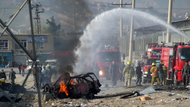 Afghan firefighters extinguish a burning car at the site of a suicide bomb attack in Kabul.