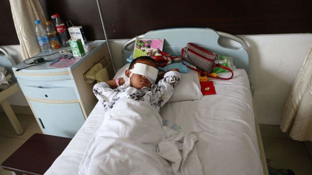 A boy lies on his hospital bed with his eyes covered with bandages in Taiyuan in north China's Shanxi province.