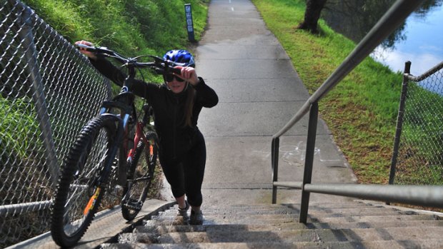 Missing link: A cyclist carries her bike up stairs on the Yarra Trail in Abbotsford.