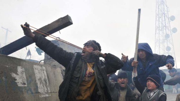 Anger erupts &#8230; a protester outside Bagram Air Base fires slingshots after rumours ran through the area that soldiers were burning copies of the Koran.