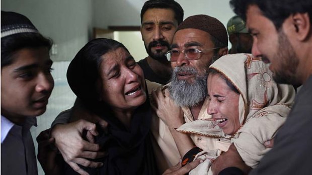 Vital work ...  the brother of Nasima Bibi, shot by a masked gunman in Karachi, comforts other relatives.