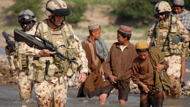 Lieutenant Colonel Stuart Yeaman followed by Afghan boys at a river crossing at Talani, southern Afghanistan.