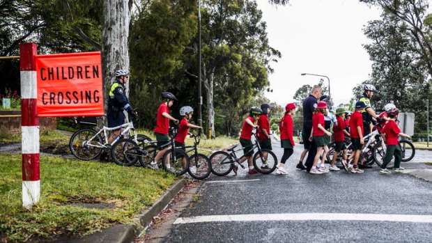 Police teach Macquarie Primary School students about road awareness outside the school yesterday.