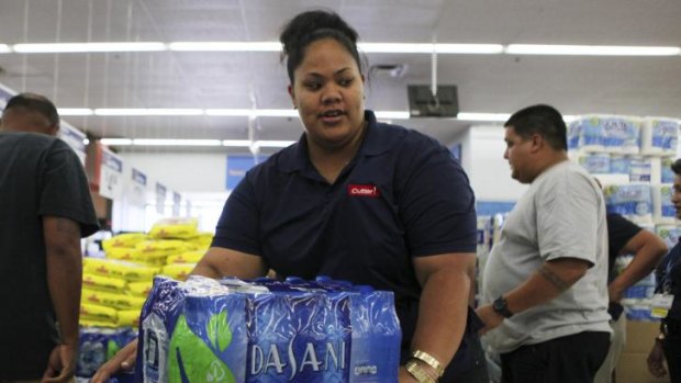 Andrea Malosa loads bottled water into her shopping cart while buying supplies in Mililani as two hurricanes  approach the Hawaiian islands.