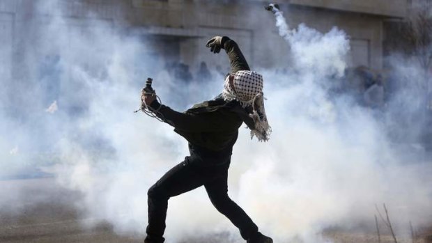A Palestinian throws back a tear gas canister fired by Israeli troops during clashes outside Israel's Ofer military prison.