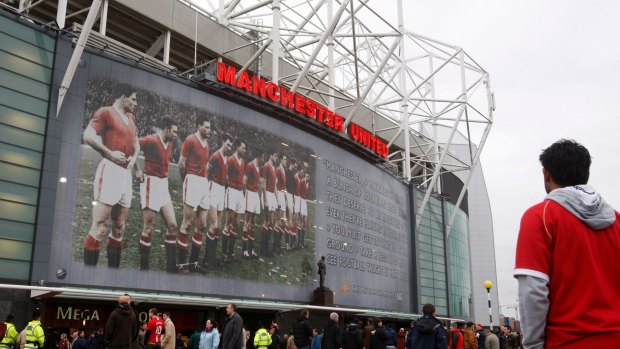 Fans walk past a poster of the Busby Babes on the front of Manchester United's Old Trafford Stadium in 2008. 