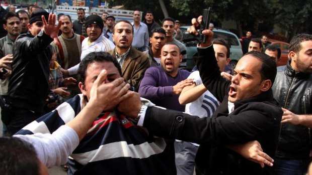 Protest: A security officer waves a gun as he arrests a member of the Muslim Brotherhood in Cairo.