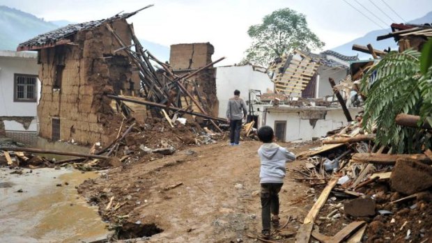 People walk past collapsed houses in Longtoushan.
