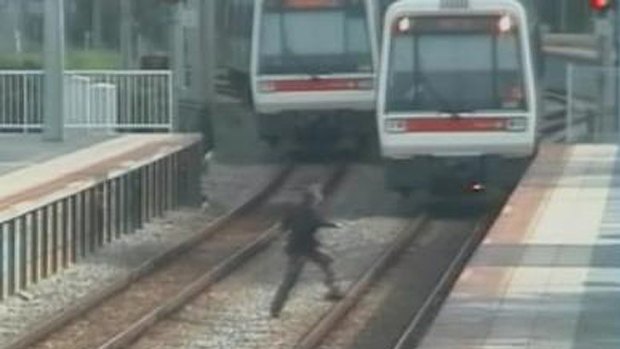 A screenshot of the CCTV footage released of people running across Perth train tracks.