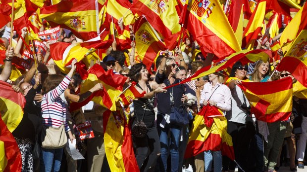 Demonstrators in Madrid hoist Spanish national flags in support of unity between Spain and Catalonia.