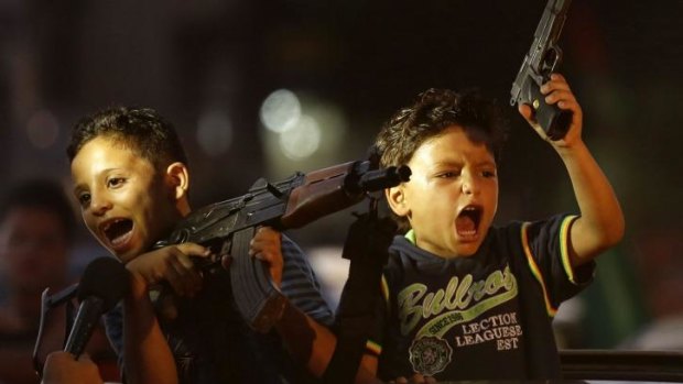 Children in Gaza hold up guns from a car as Palestinians gather in the streets to celebrate the truce.