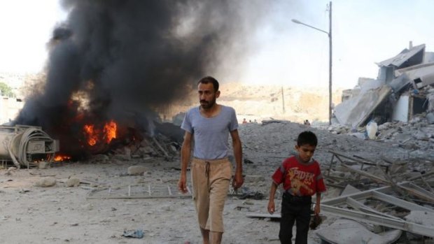 A man and a child walk past debris following a reported air strike by Syrian government forces.
