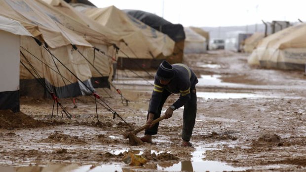 Swamped &#8230; a refugee tries to remove the mud and water from around his tent in the Zaatari refugee camp in Jordan.