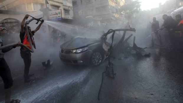 Palestinians help extinguish the fire after an Israeli air strike on the car of Hamas's top commander.