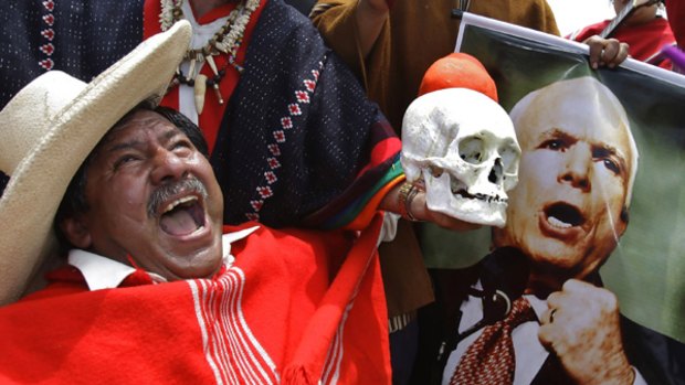 Peruvian faith healers - one holding a skull - with a poster of Senator John McCain during a cleansing ritual on La Herradura Beach in Lima.