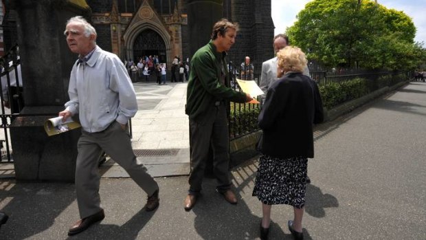 Hear this: Clergy abuse activist Mark Fabbro hands out flyers outside Melbourne's St Patrick's Cathedral.