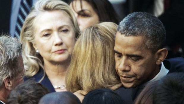 Then US Secretary of State Hillary Clinton looks on as US President Barack Obama hugs a State Department employee on September 12, 2012, a day after  the killing of US Ambassador to Libya Christopher Stevens and three staff members.