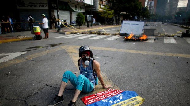 An anti-government demonstrator rests on the ground near a barricade in Caracas.