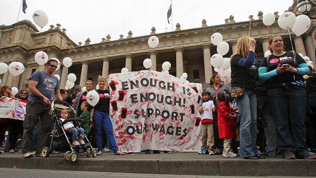 Childcare workers and parents rally on the steps of parliament.