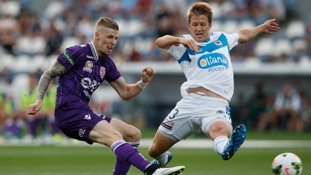 Andy Keogh of Perth Glory scores as Adrian Leijer of Melbourne Victory tries to defend.