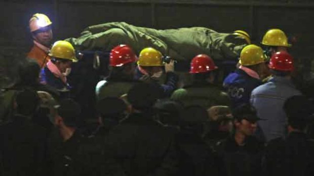 Rescue workers carry a survivor on a stretcher to a waiting ambulance at the Wangjialing Coal Mine in Xiangning county.