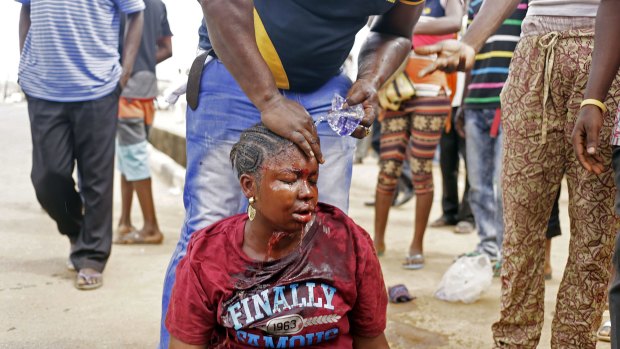 A man washes the face of a female voter beaten by a Nigerian policewoman at a polling station in Lagos during an altercation on Saturday. The policewoman was later arrested for misconduct.