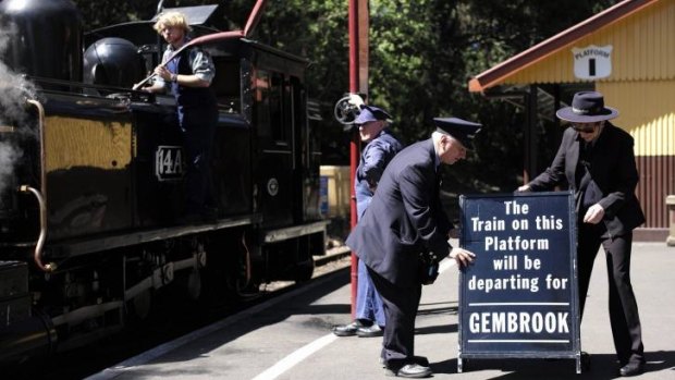 Staff at the Puffing Billy railway station of Lakeside put out a sign for the next arriving train as locomotive 14A is watered on the platform.