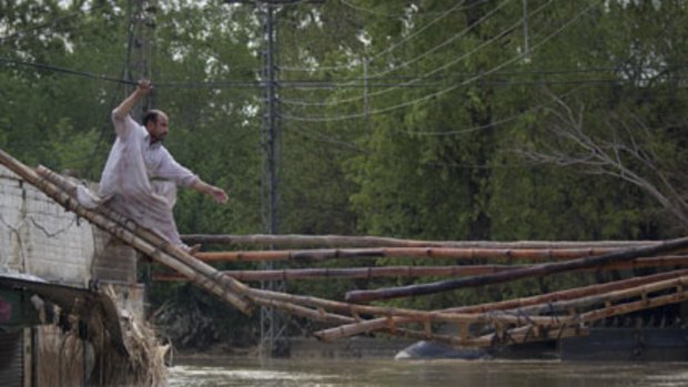 Endless struggle ... a man tries to cross a makeshift bridge to escape his flooded home in Nowshera.