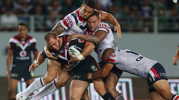 Caught: Simon Mannering is swamped by Roosters.
