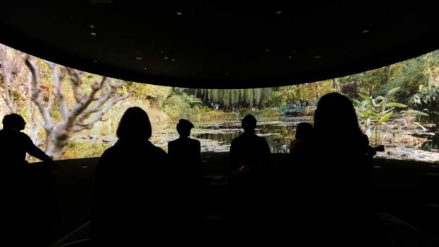 Visitors view a 180-degree video installation of Monet's garden at the NGV.
